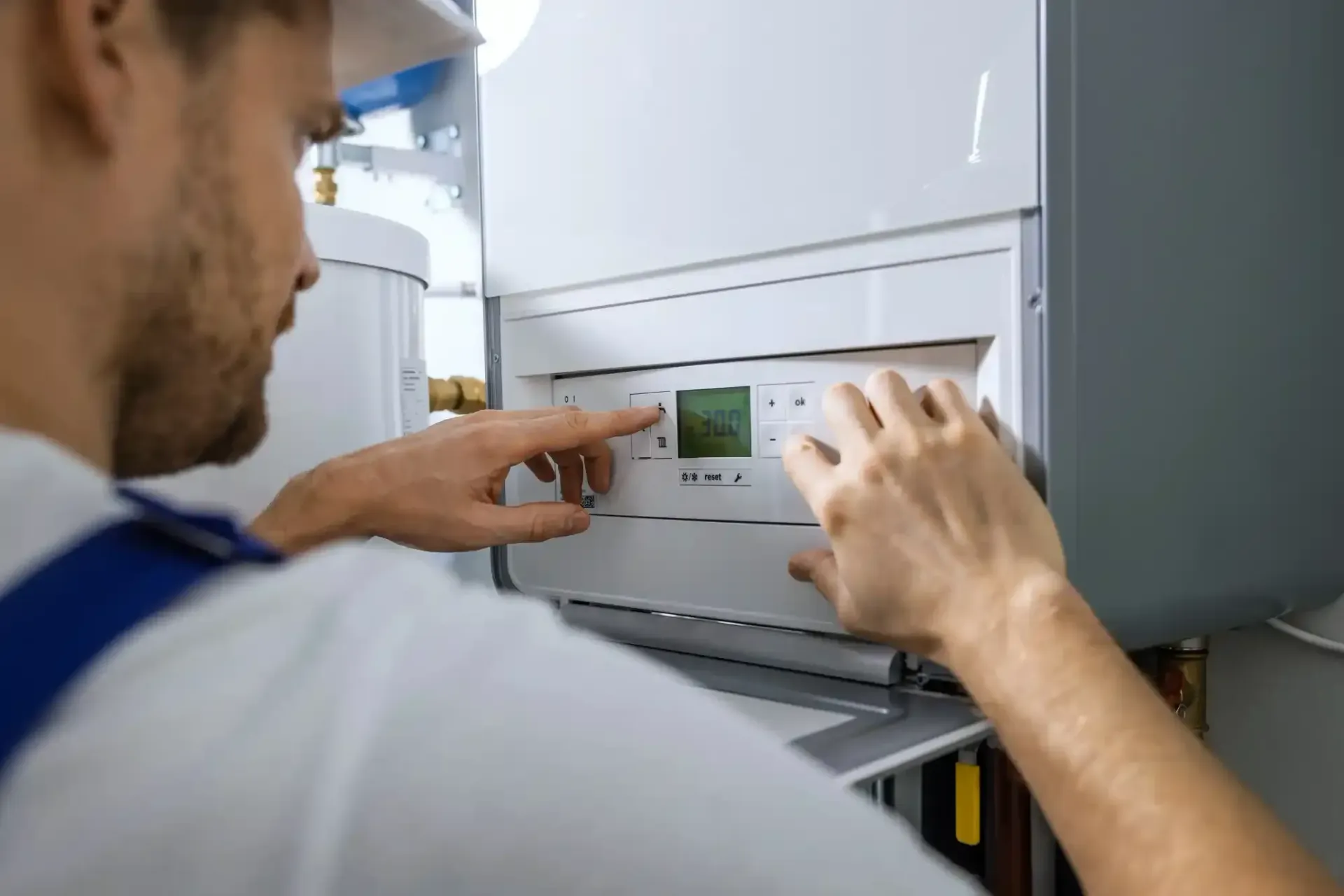 Tecnico che regola i comandi di una caldaia per il riscaldamento domestico